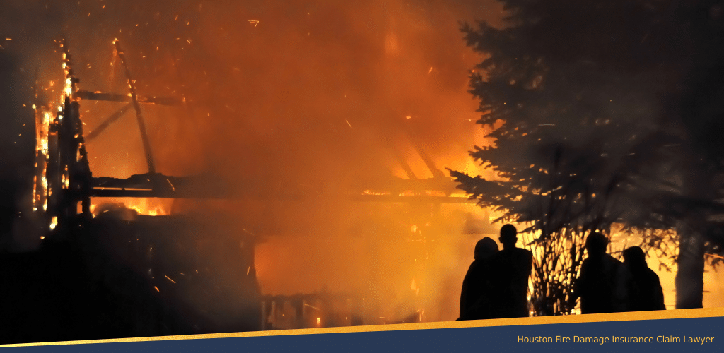 Silhouetted figures watch a house engulfed in flames at night, representing fire damage and the need for insurance claim assistance.